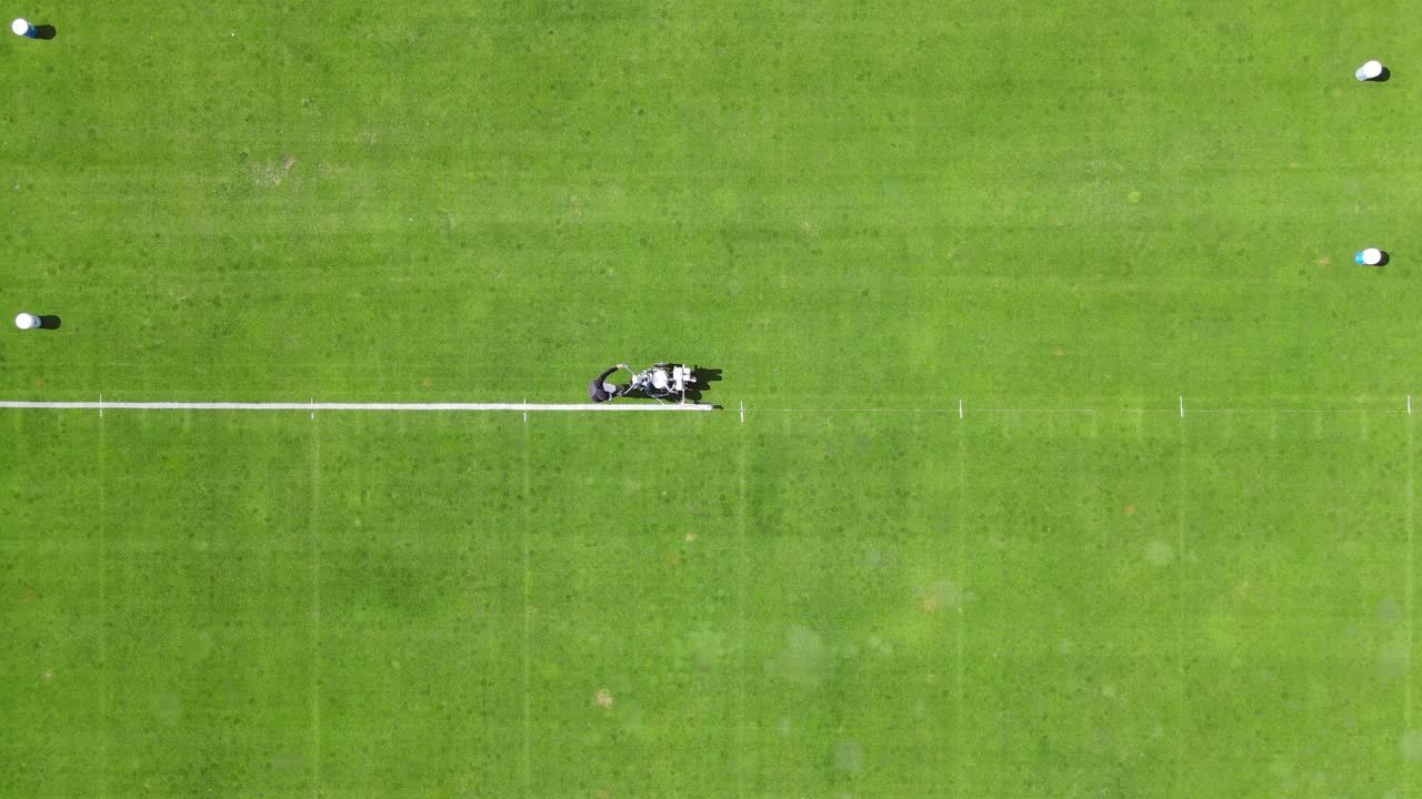 여름 에 잔디 축구장 에서 사이드 라인 을 칠 하기 위해 기계 를 밀고 있는 승무원 들 의 공중 위 아래  ⁇