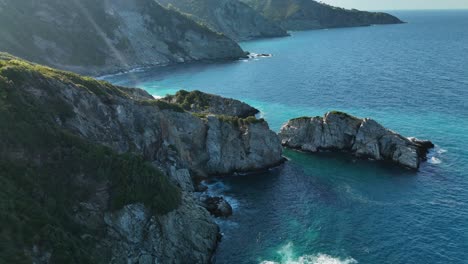 rugged coastal cliffs and turquoise sea water during a sunny day, aerial view