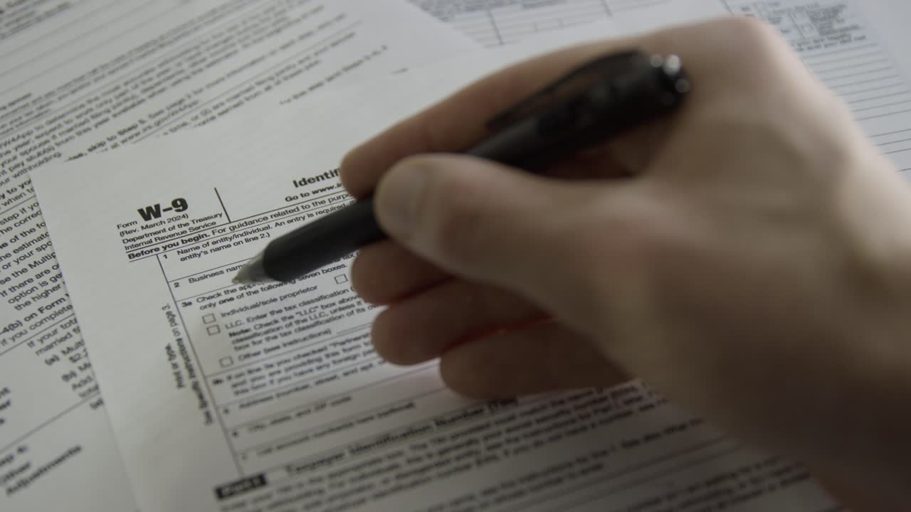 Person filling out a W-9 form. Request for Taxpayer Identification Number and Certification. Person filling out tax form from IRS