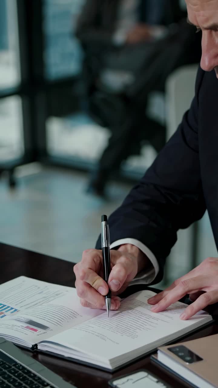 Un uomo professionista in giacca e cravatta scrive in un quaderno. L'angolazione ravvicinata cattura l'attenzione e i dettagli