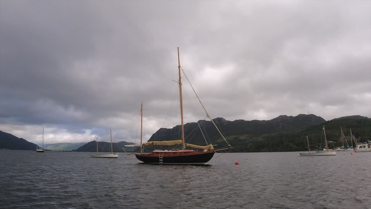 vista desde el barco: a la deriva más allá de un gran yate de vela de dos mástiles bajo las nubes