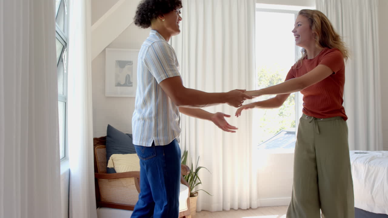 Dancing joyfully together, diverse couple celebrating sunny day at home