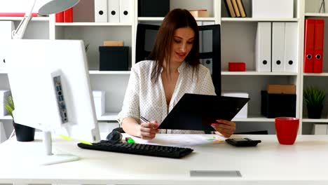 mujer de negocios trabajando en una computadora en una oficina ligera y mirando a la cámara