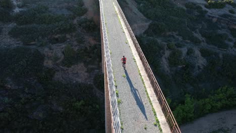 Motociclista-Sobre-Un-Viejo-Puente-En-La-Tarde,-Siguiendo-El-Modo