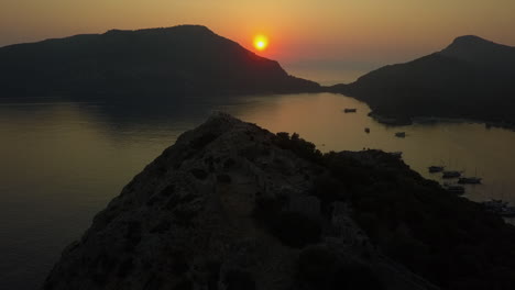 Golden-orange-sunset-aerial-orbits-rocky-peak-on-Mediterranean-island