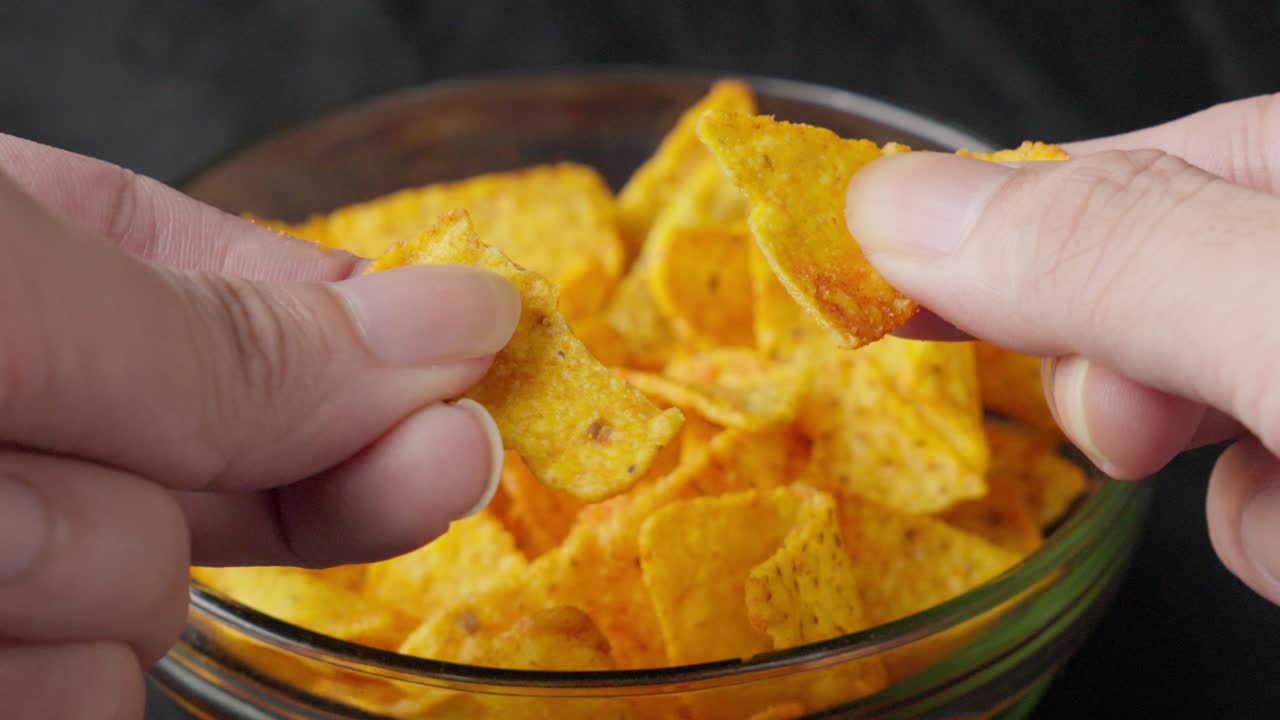 Tortilla chips tagliate e spezzate da mani bianche di un uomo caucasico, primo piano, cibo, piatto snack in stile messicano.