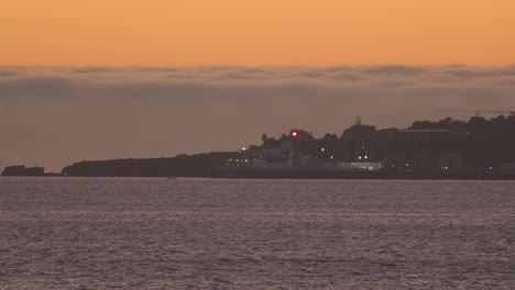 Puesta-De-Sol-Sobre-La-Ciudad-Y-El-Mar-En-Cascais-Con-El-Faro-Dando-Luz,-Portugal