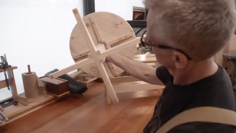 woodworker examines hand made table in wood shop