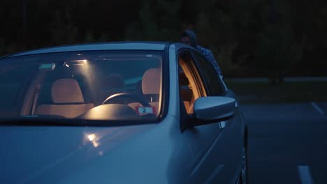 young man getting out of a car going through a car door at night in the dark