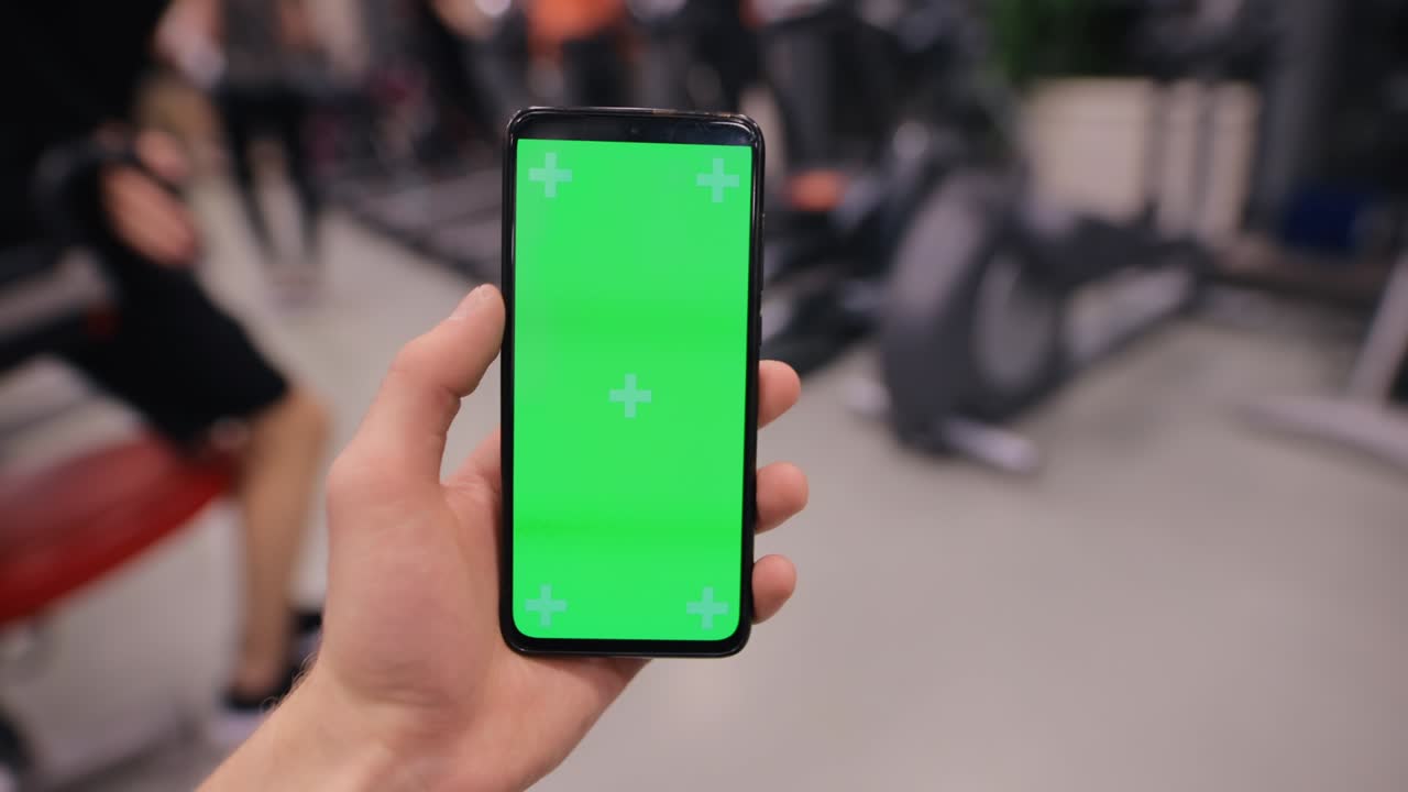 체육관 에서 남자 손 에 있는 스마트폰 의 초록색 화면