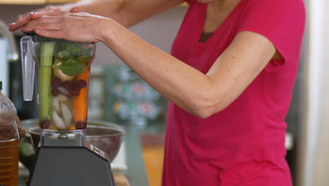 a female begins to blend a mix of many vegetables stuck in a blender for a nice green smoothie for an excellent breakfast