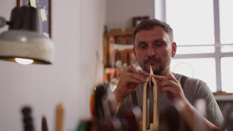 hombre cosiendo cuero natural con hilo encerado en una tienda de artesanía