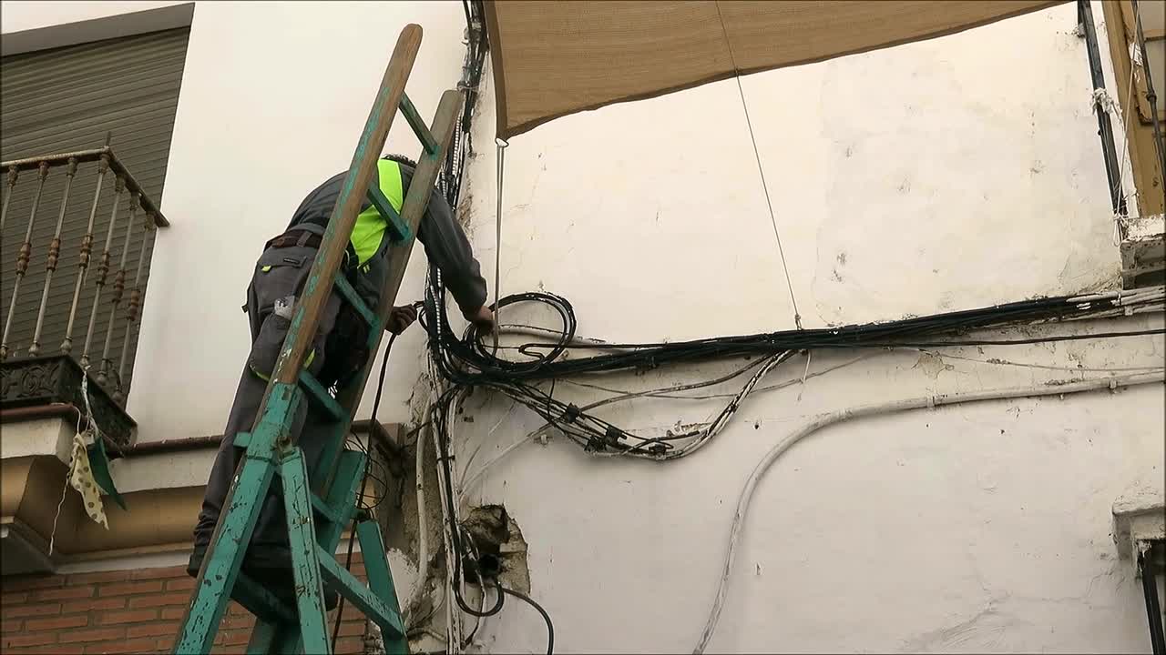 Alora, Spain - November 6, 2018: Men stringing electric cables above busy village street for Christmas lights