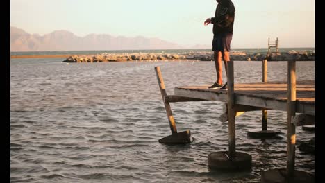 african american male jogger relaxing on pier at beach in the sunshine 4k