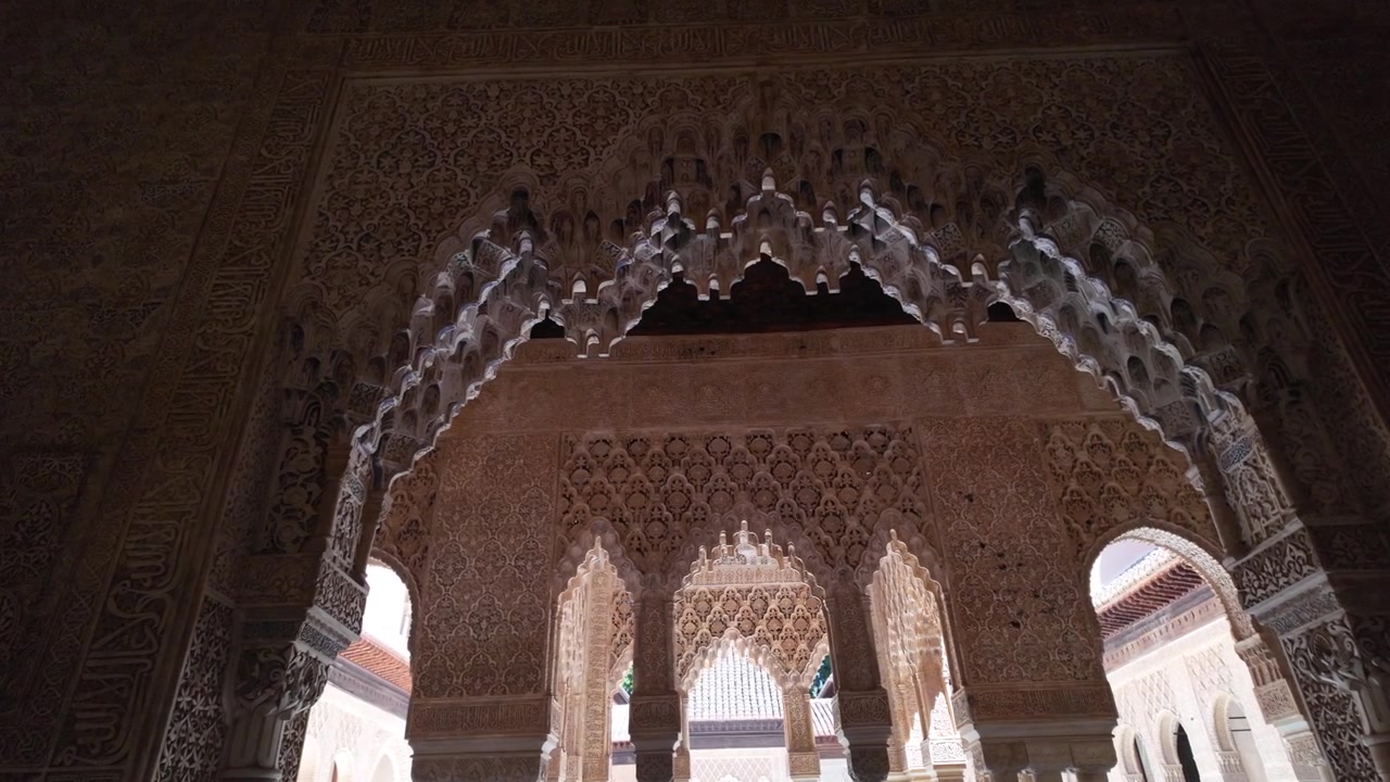 Panoramica al rallentatore attraverso intricati archi a muqarnas e ornamenti in stucco intagliato all'interno dei Palazzi Nasridi dell'Alhambra a Granada, Spagna.