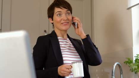 Woman-using-smartphone-while-holding-coffee