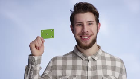 young and handsome man holding buisness card next to his face
