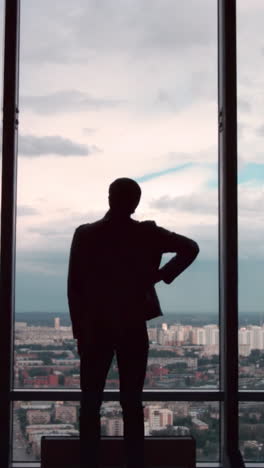 man contemplating cityscape from skyscraper window