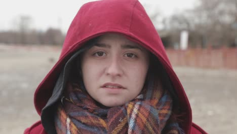 a woman wearing dark red hood looking pale and sad - close up shot