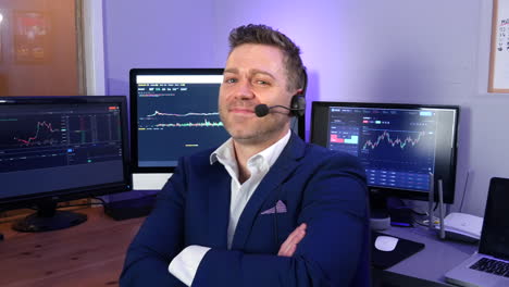 portrait of a happy successful forex cryptocurrency trader analyst broker smiling in his office with stock market graphs on screens behind him