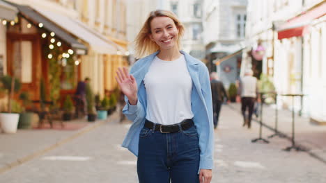 woman tourist smiling friendly at camera waving hands gesturing invitation hello hi greeting goodbye