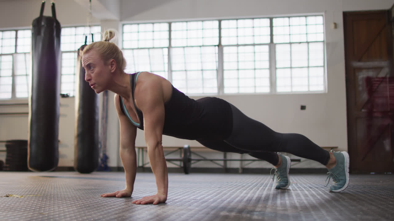 Fit caucasian woman performing push up exercise at the gym