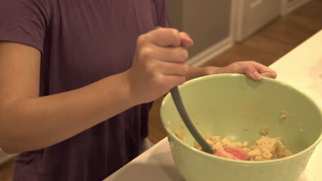 una joven coreana mezcla contenido en un tazón grande mientras hace galletas de mantequilla millonarias