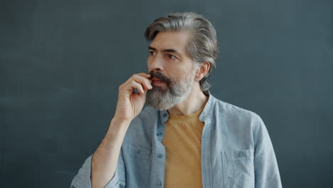 man with gray hair and beard in thoughtful pose