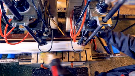 worker operates with plastic detail on industrial machine.