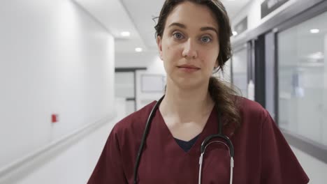 portrait of happy caucasian female doctor in hospital corridor, slow motion