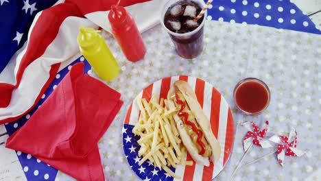 perrito caliente, papas fritas y bebida fría servida en una mesa con tema del 4 de julio