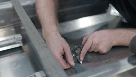 man using a digital caliper to measure the dimensions of aluminum metal in the workshop