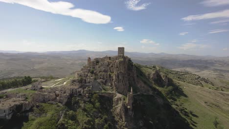 Drone-Volando-Lentamente-Y-Un-Poco-De-Lado-Hacia-Las-Antiguas-Ruinas-De-Craco-En-Una-Colina-En-El-Sur-De-Italia-En-4k