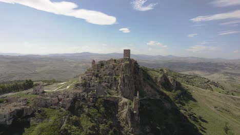 drone volando lentamente y un poco de lado hacia las antiguas ruinas de craco en una colina en el sur de italia en 4k