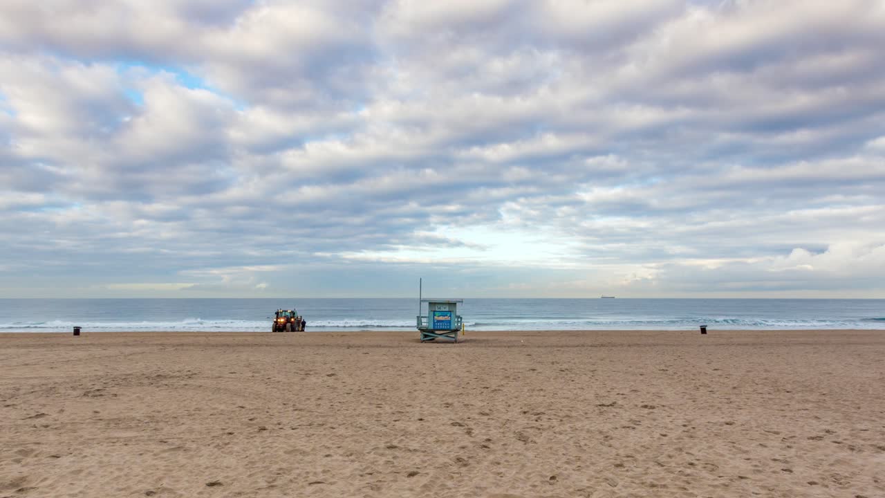 personas caminando en la playa de manhattan durante una puesta de sol nublada cerca del puesto de socorristas