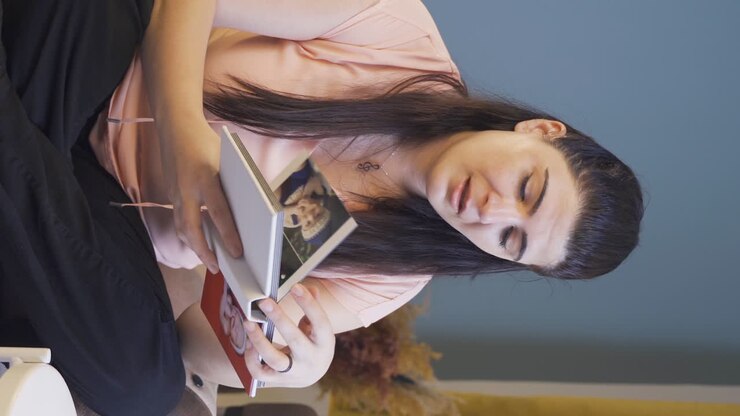 Vertikální video: Žena prohlížející si rodinné album pláče.