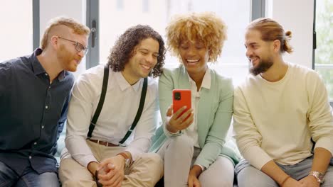 Multi-ethnic coworkers using phone sitting relaxed during a break