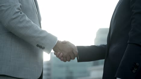 slow motion shot of colleagues shaking hands outdoor