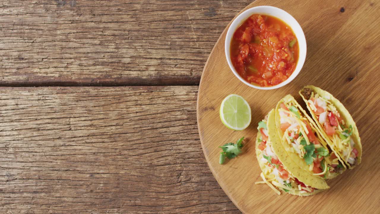 video de tacos recién preparados y un tazón con salsa a bordo en una superficie de madera