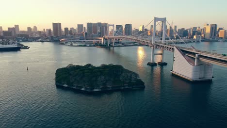 aerial drone flying around rainbow suspension bridge in odaiba tokyo city japan during sunset