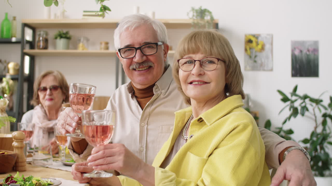 Retrato de pareja de mayores alegre con bebidas en cena en casa