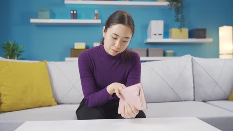 poor and desperate asian woman looking for money in her empty wallet.