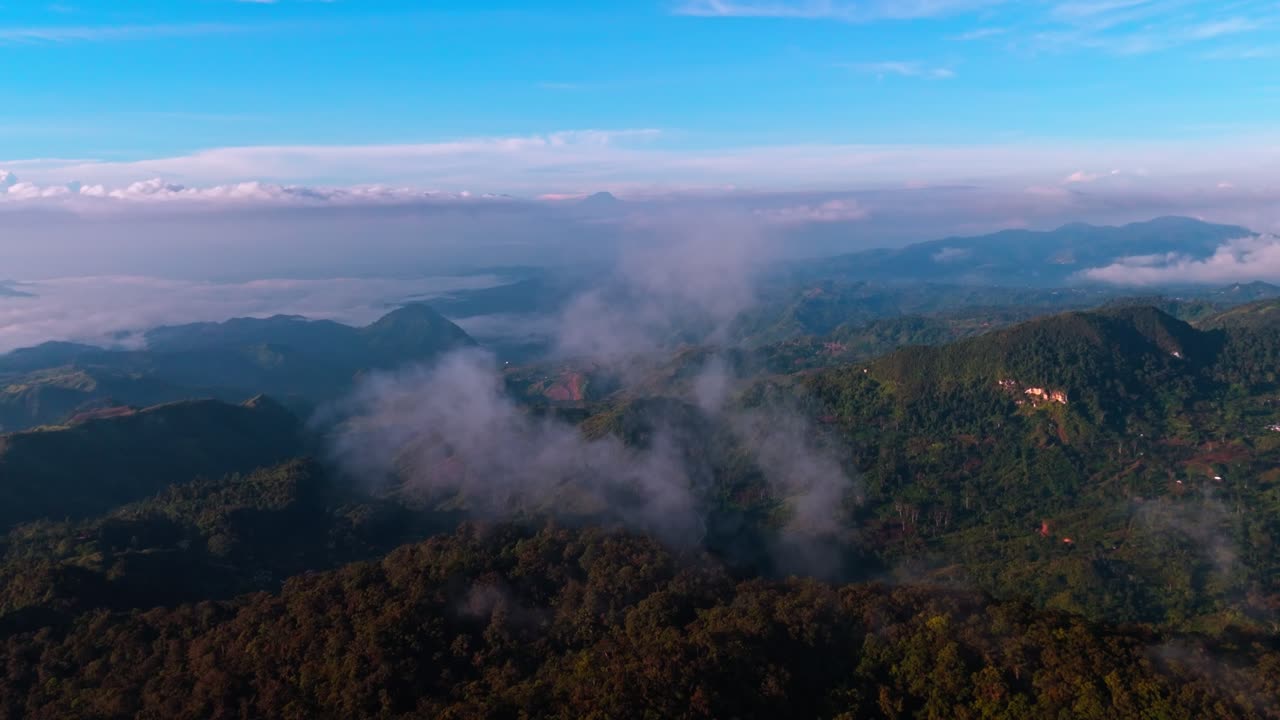 Vista aerea 4K da drone delle nuvole mattutine che fluttuano sopra le lussureggianti catene montuose filippine, che mostra valli nebbiose, colline stratificate e cielo luminoso in un pittoresco paesaggio tropicale all'alba
