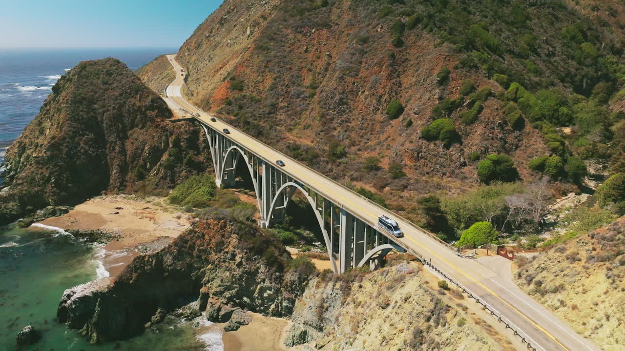 Beautiful bridge connecting the mountains for cars to pass. Lovely sight of Pacific coastline of sunny California from bird's eye view.
