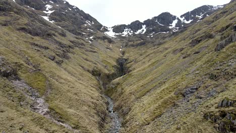 tomada con un avión no tripulado de la escocia rural, donde el encanto rústico se encuentra con la naturaleza impresionante, capturando vistas aéreas de tranquilos valles nevados y torrentes serpenteantes