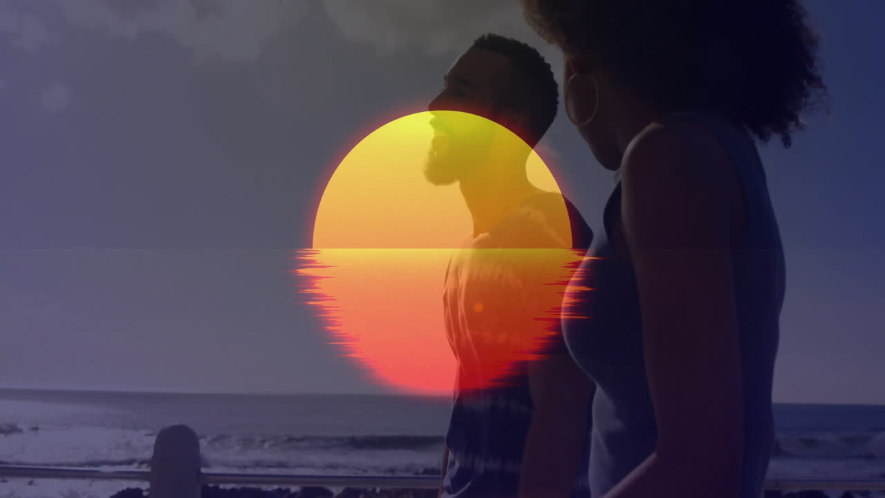 Silhouetted couple walking on beach with vibrant sunset animation overlay