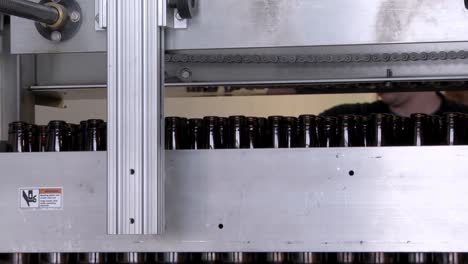 production worker or brewer sorting and examing bottles on the production - bottling line ready to be filled with beer.