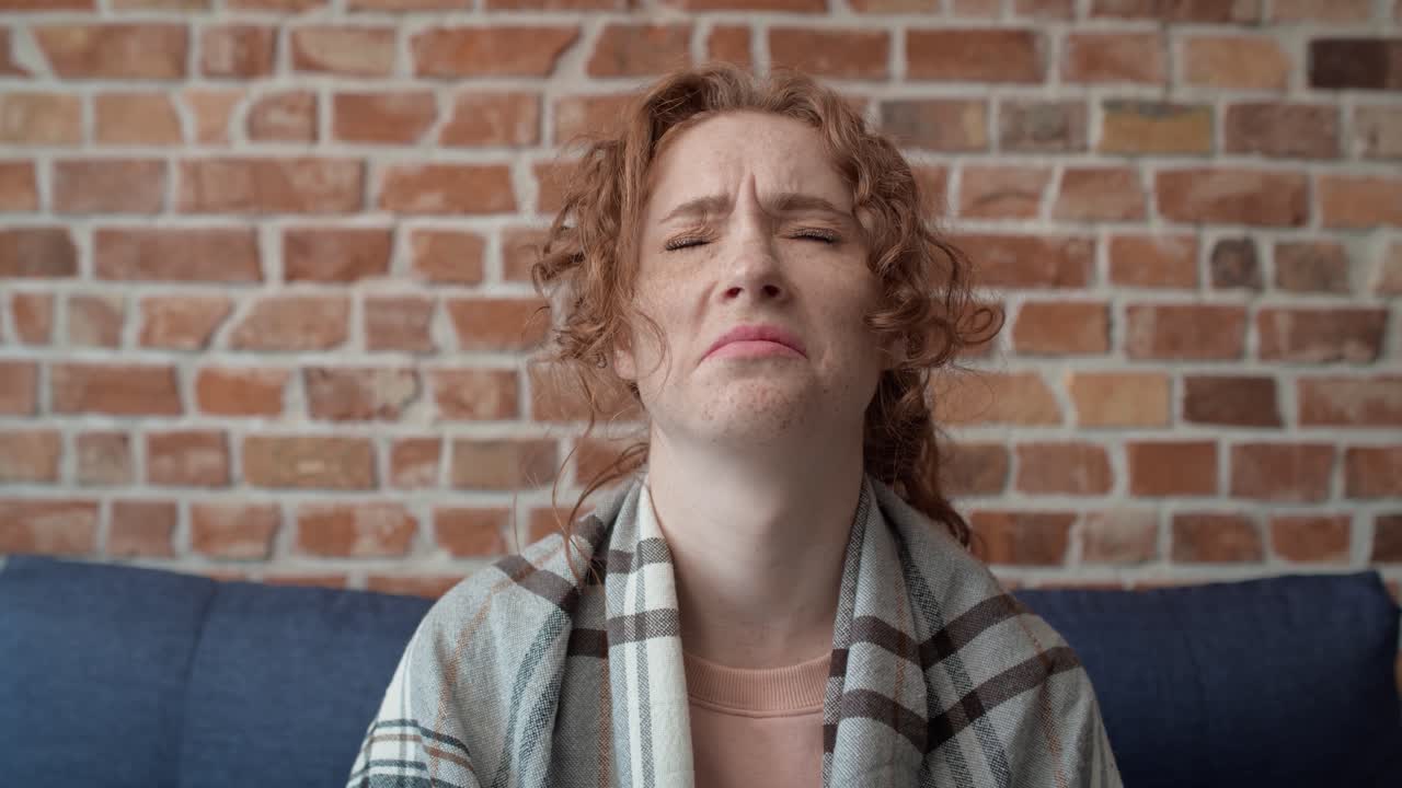 video de una joven caucásica cubierta con una manta cayendo en el sofá