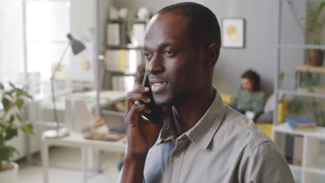 Black-Man-Talking-on-Mobile-Phone-in-Office