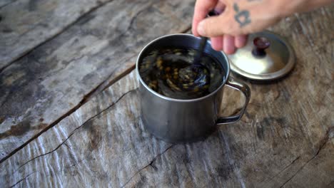 revolviendo a mano hojas de té de guayusa saludables en agua caliente sobre una mesa de madera